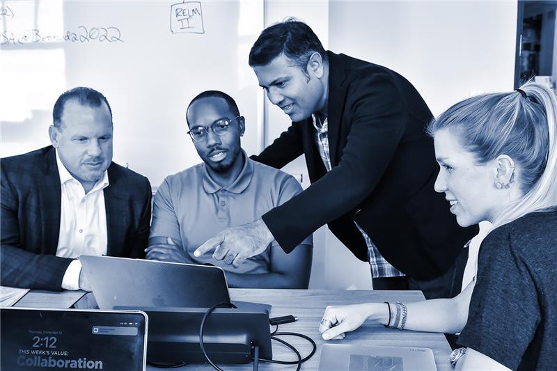 four people looking at a laptop