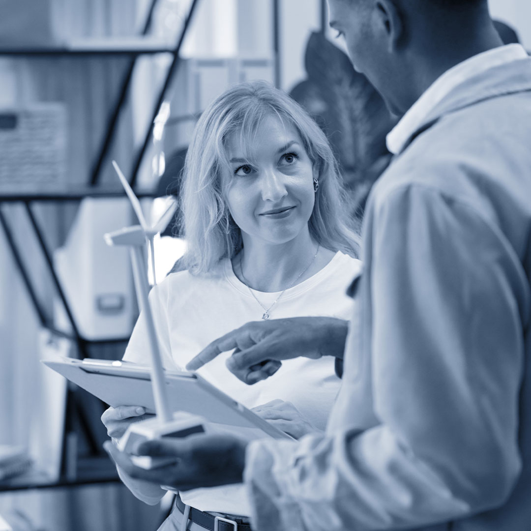 Woman and man look at data with a model of a wind turbine
